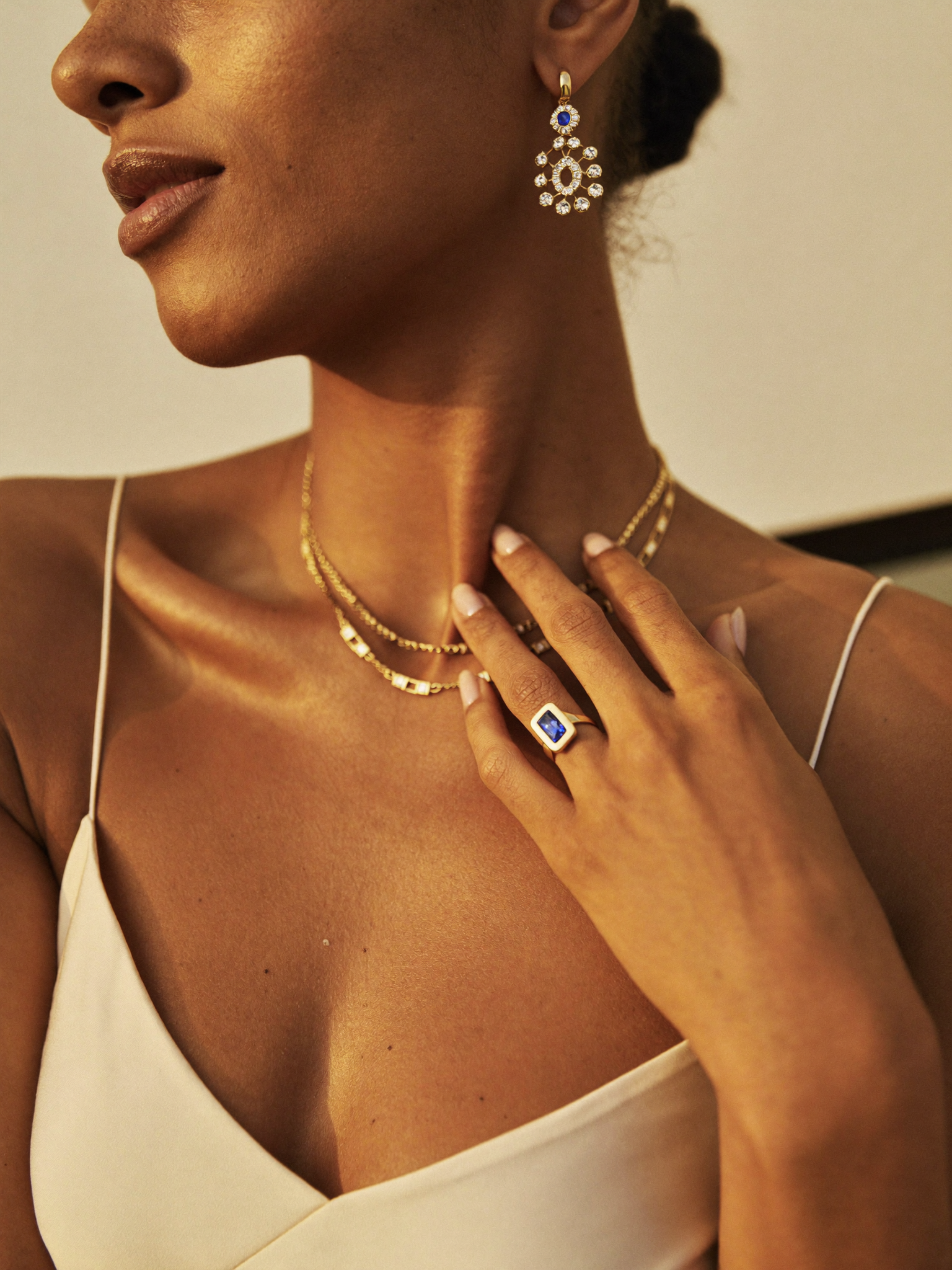 Modelo com joias JLópez — brinco safira, correntes layered e anel · estilo editorial Cartier