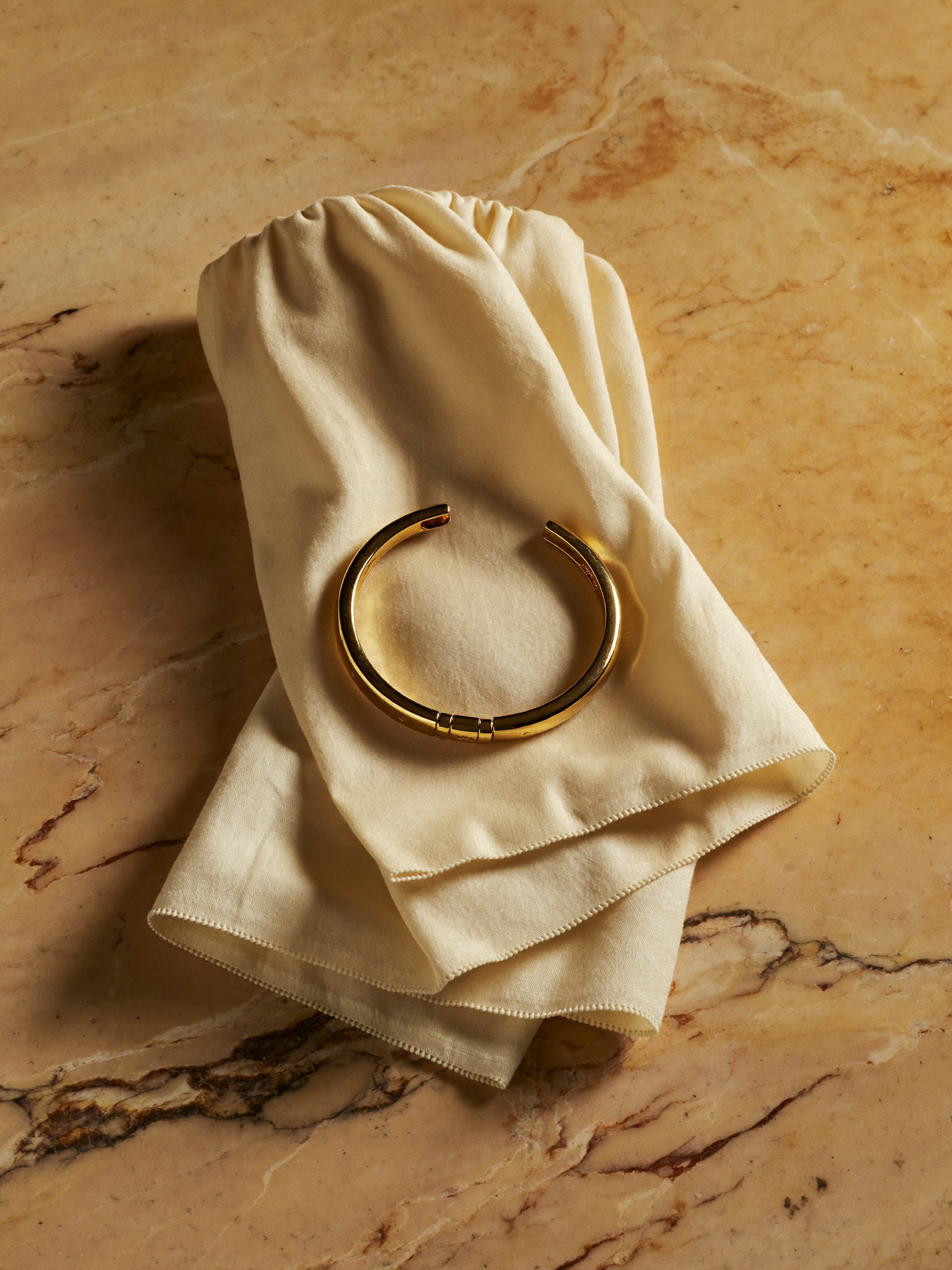 Bangle de ouro 18k JLópez sobre seda marfim e mármore Calacatta · still-life editorial